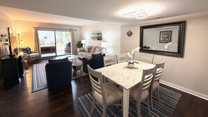 Una sala de estar moderna con comedor, un conjunto de sofás, una mesa de centro y un ventanal grande.