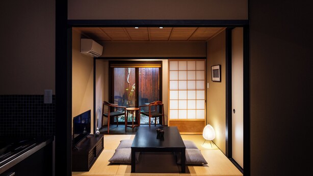Une pièce de style japonais traditionnel, avec un sol recouvert de tatamis, une table basse et une porte coulissante donnant sur un jardin.