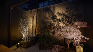 Un jardin avec une clôture en bois, un chemin de gravier et différentes sortes de plantes.