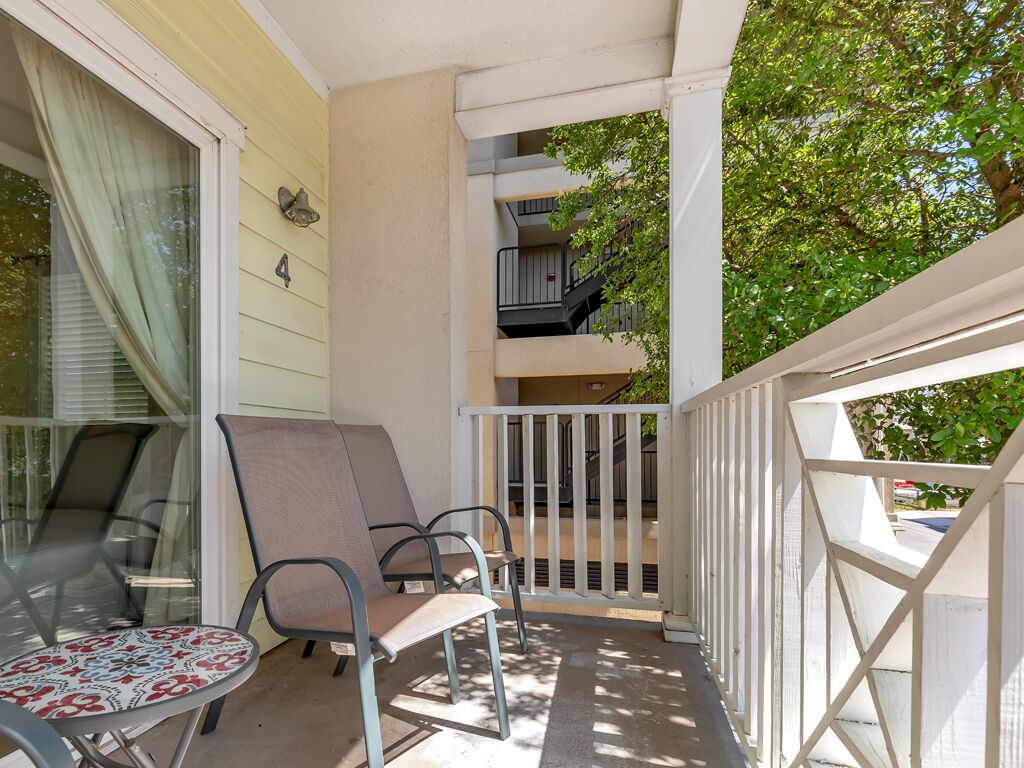 Un balcon avec deux chaises et une table, une balustrade blanche et une vue sur un immeuble doté de nombreux balcons.