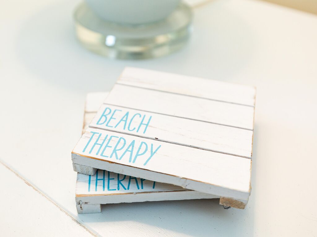 A stack of white wooden boards with the words "BEACH THERAPY" written on them.