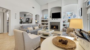 A spacious living room with a fireplace, a sofa set, and a television. - Seagrove Beach Home + Carriage House + Bikes (Santa Rosa Beach)