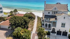 A coastal property with a beach view, a paved pathway, and a large tree in the foreground. - Seagrove Beach Home + Carriage House + Bikes (Santa Rosa Beach)