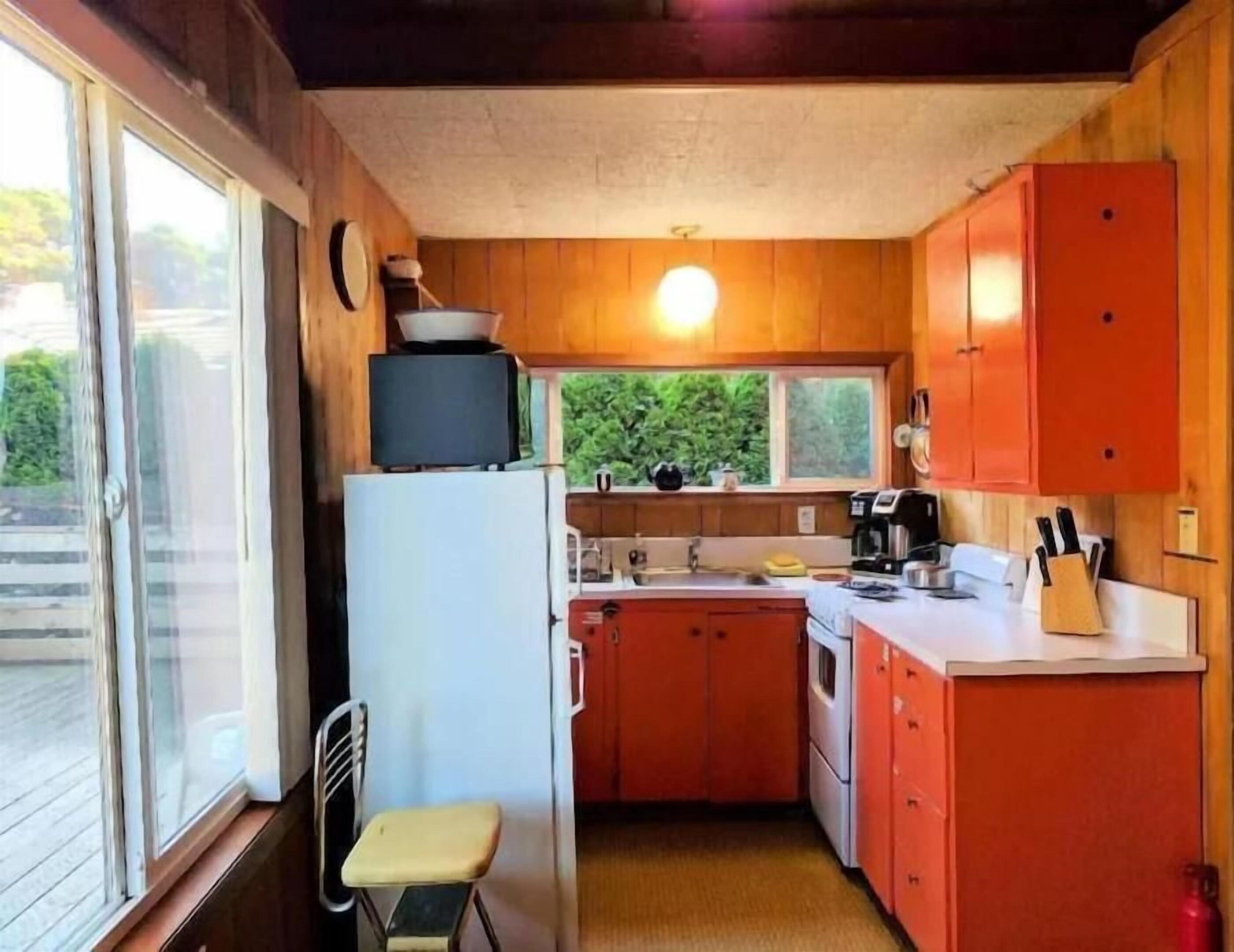 A compact kitchen with wooden cabinets, a refrigerator, a sink, and a stove.