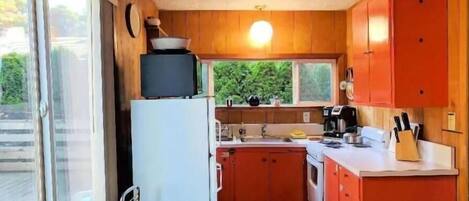 A compact kitchen with wooden cabinets, a refrigerator, a sink, and a stove.