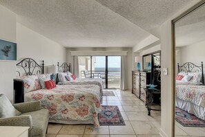 Habitación de hotel con dos camas, un aparador, un espejo y vista al océano.