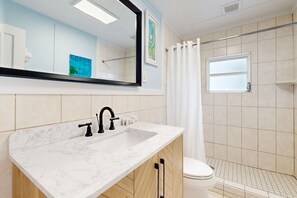Bathroom features a large mirror, shower area, and a window.