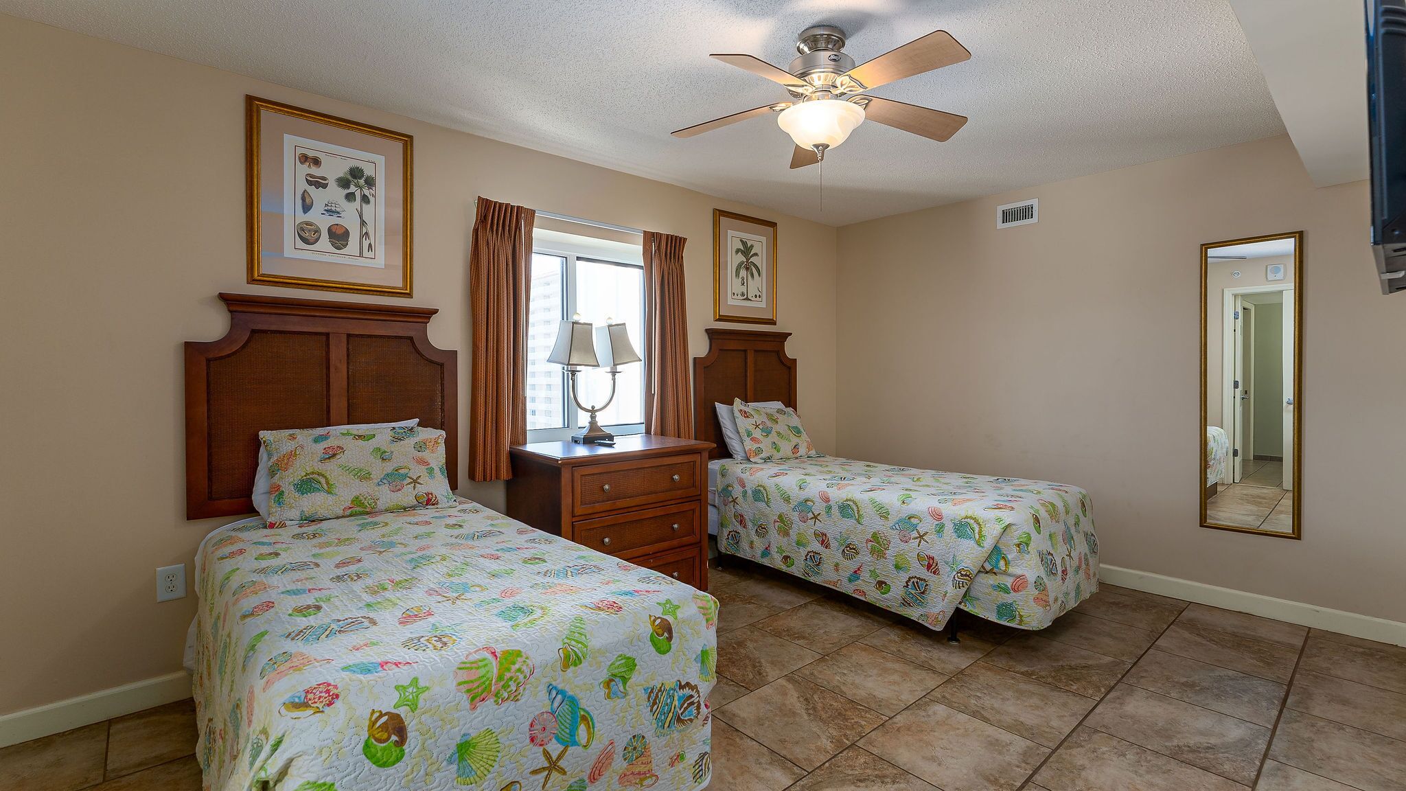 A bedroom with two beds, a ceiling fan, and a dresser.