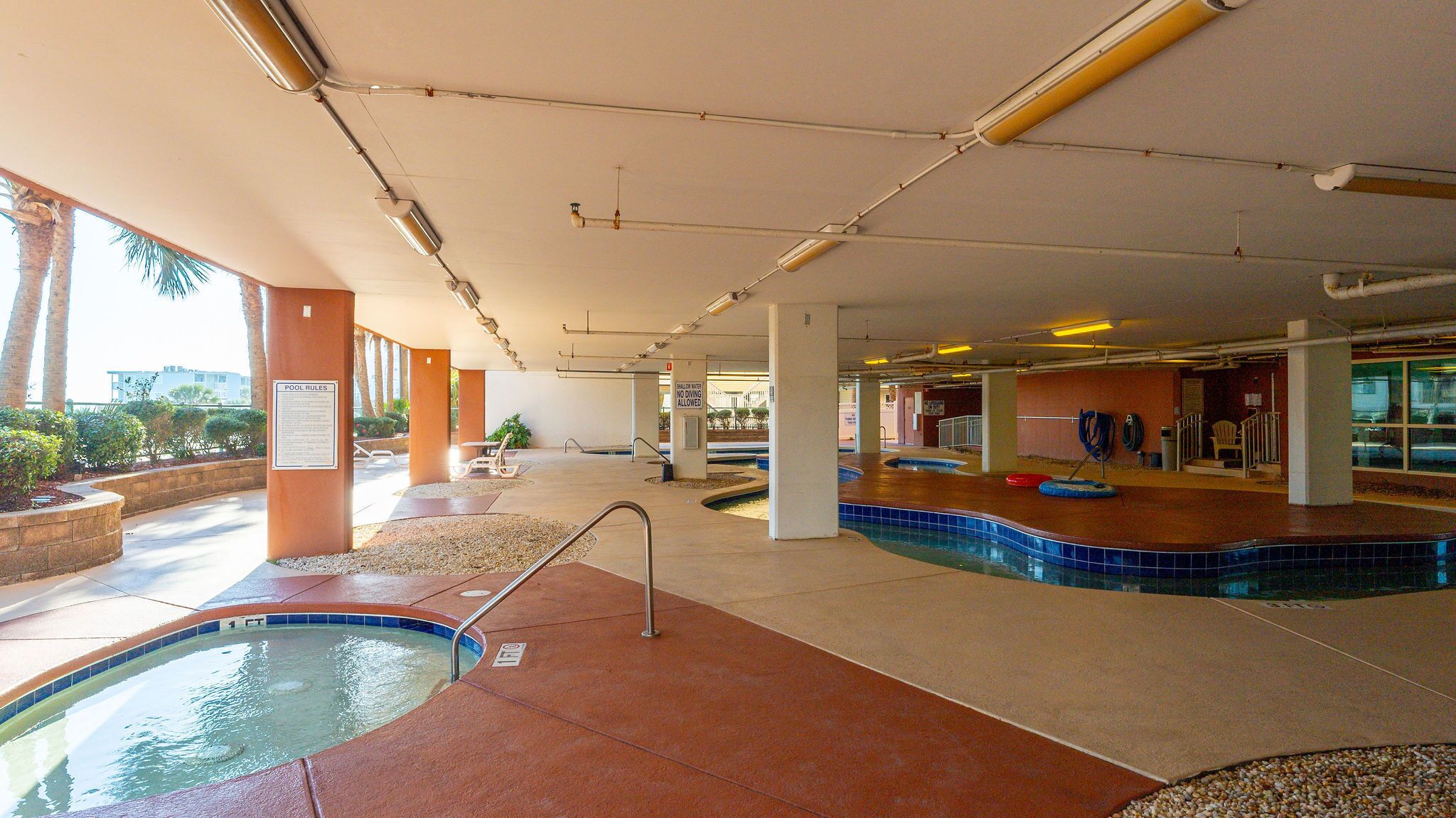 An indoor swimming pool area with a pool, lounge chairs, and a sign indicating no diving allowed.