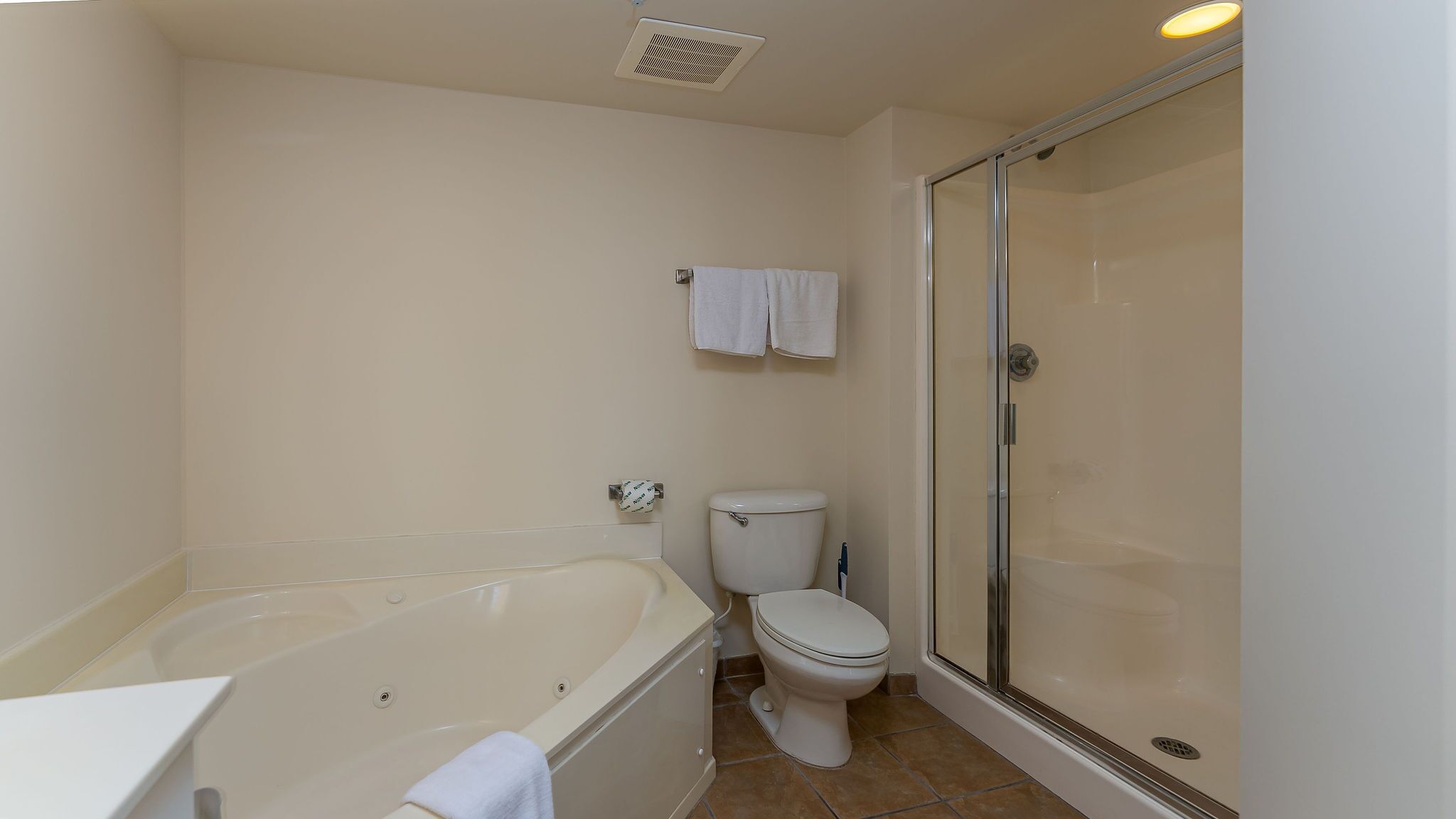 A bathroom with a bathtub, toilet, and glass-enclosed shower stall.