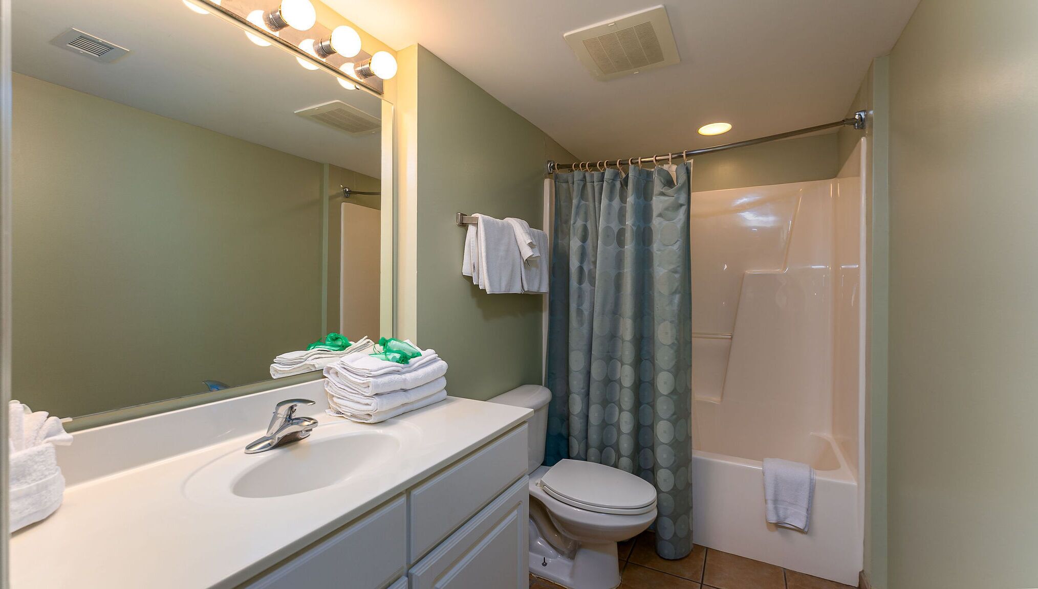 A bathroom with a sink, mirror, toilet, and shower curtain.