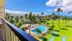 A resort with a swimming pool surrounded by palm trees and a golf course. - Top floor oceanfront 2 bedroom Maui condo (Kihei)