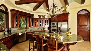 A spacious kitchen with a large island, wooden cabinets, and a chandelier.