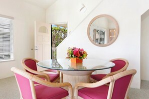 A dining area with a glass table, wicker chairs, and a vase of flowers. - Regency 520 Spacious Affordale By Suite Paradise (Koloa)