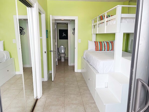 Una habitación con literas, un baño con inodoro y una puerta que da a otra estancia.