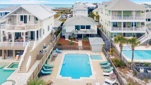 Un resort con varias construcciones, una piscina central y vista al mar.