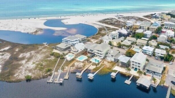 Vista aérea de una zona residencial costera con casas, una playa y un puerto deportivo.