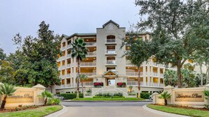 A multi-story hotel with a central entrance, surrounded by lush greenery and palm trees. - 6304 Hampton Place- Oceanfront Views, Pool, Spa & So Much More! (Hilton Head Island)
