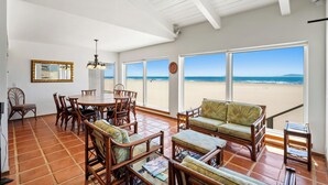 Un vaste espace de vie comprenant une grande table à manger, des sièges confortables et une vue sur la plage.