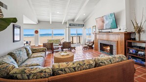 Un salon spacieux avec un grand canapé d’angle, une cheminée et un téléviseur. Un panneau est accroché au mur, sur lequel on peut lire : « Hollywood Beach ».