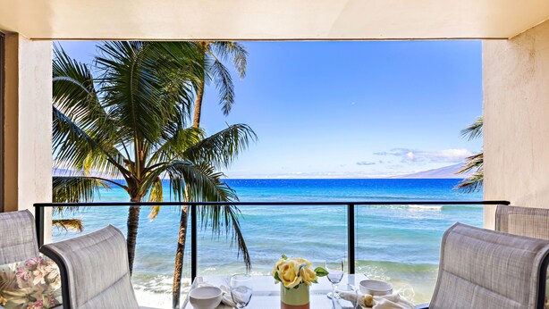 A dining table with chairs and a view of the ocean. - Timeless Island Charm with Stunning Ocean View (Lahaina)