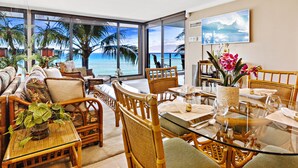 A room with a glass table, wicker chairs, and a view of the ocean. - Timeless Island Charm with Stunning Ocean View (Lahaina)