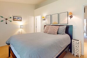 Cozy retreat with a large bed, wall-mounted light, and framed artworks.