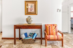 A wooden desk with a vase, a wicker basket, and a colorful chair.