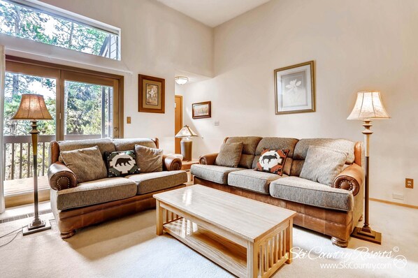 Ein Wohnzimmer mit zwei Sofas, einem Couchtisch und zwei Stehlampen.