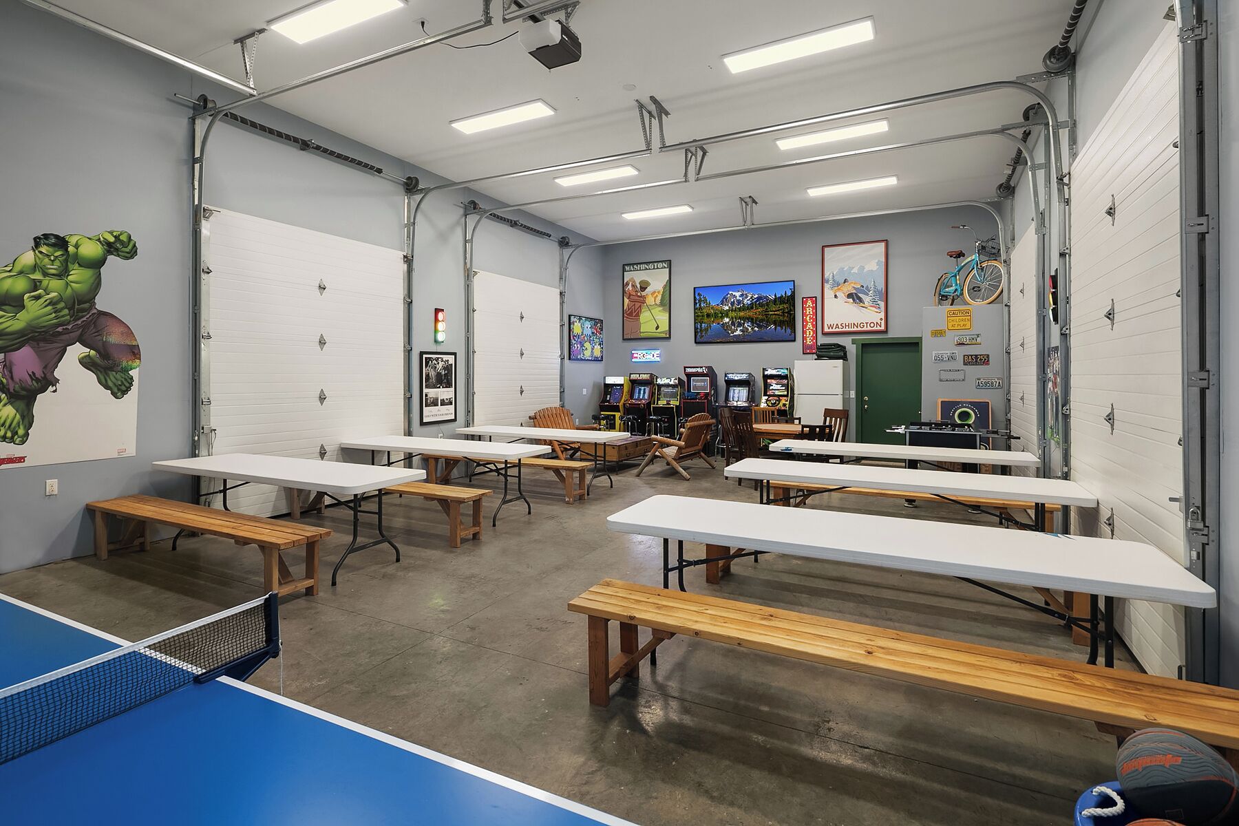 A room with tables, benches, and arcade games.