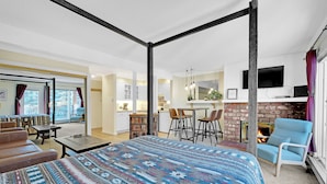 A spacious bedroom with a large bed, a sitting area with a coffee table, and a view of the kitchen and living area. - This Location Can’t Be Beat! Cozy Studio in Downtown Breckenridge l DS109 (Breckenridge)