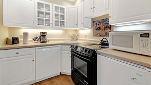A kitchen with white cabinets, a black stove, a microwave, and a coffee maker. - This Location Can’t Be Beat! Cozy Studio in Downtown Breckenridge l DS109 (Breckenridge)