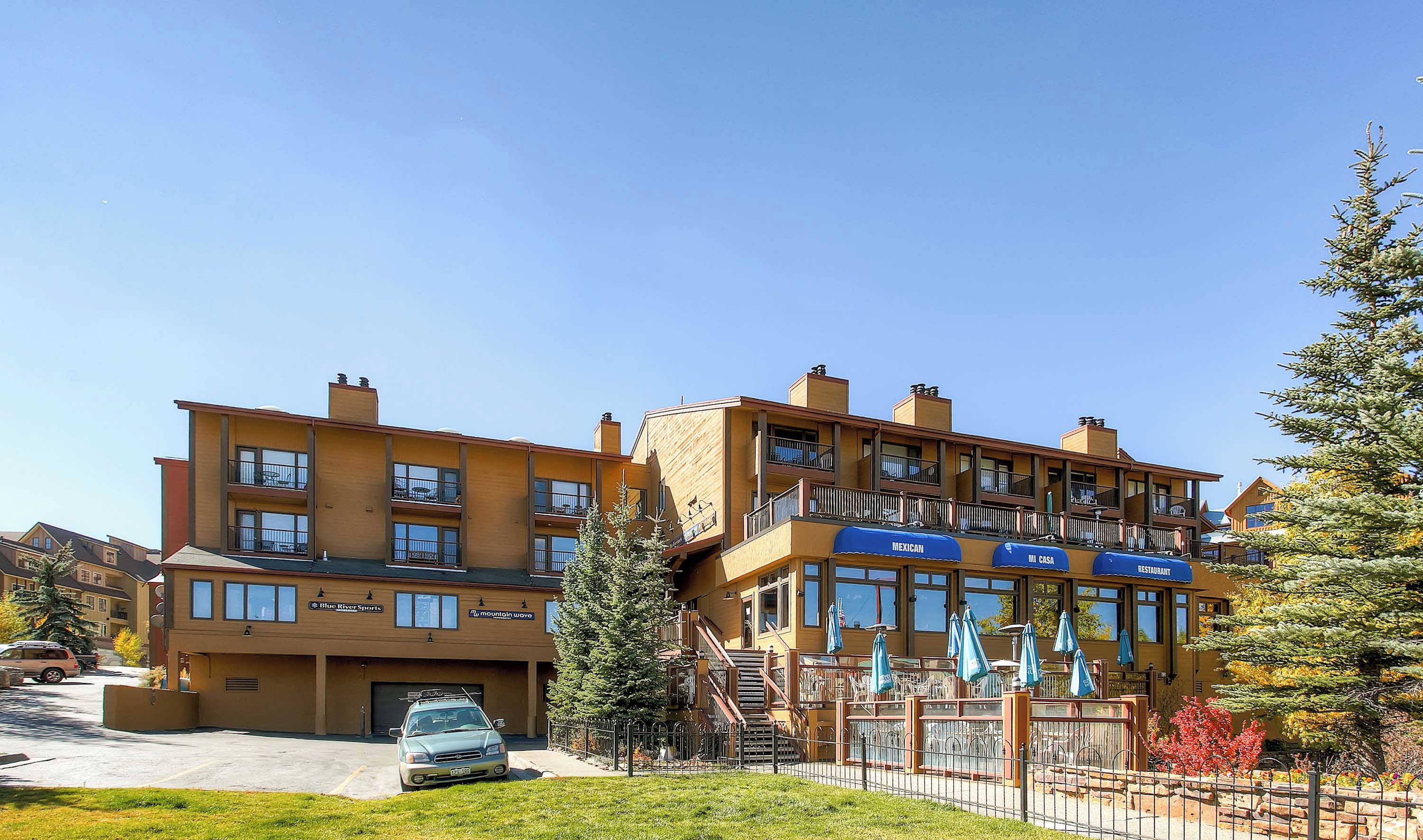 Ein mehrstöckiges Hotel mit Restaurant im zweiten Stock, Außenbereich und Parkplatz.
