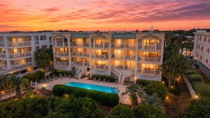 Um hotel com vários andares, varandas, piscina e jardins ajardinados.