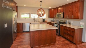 A modern kitchen with wooden cabinets, stainless steel appliances, and a large island.