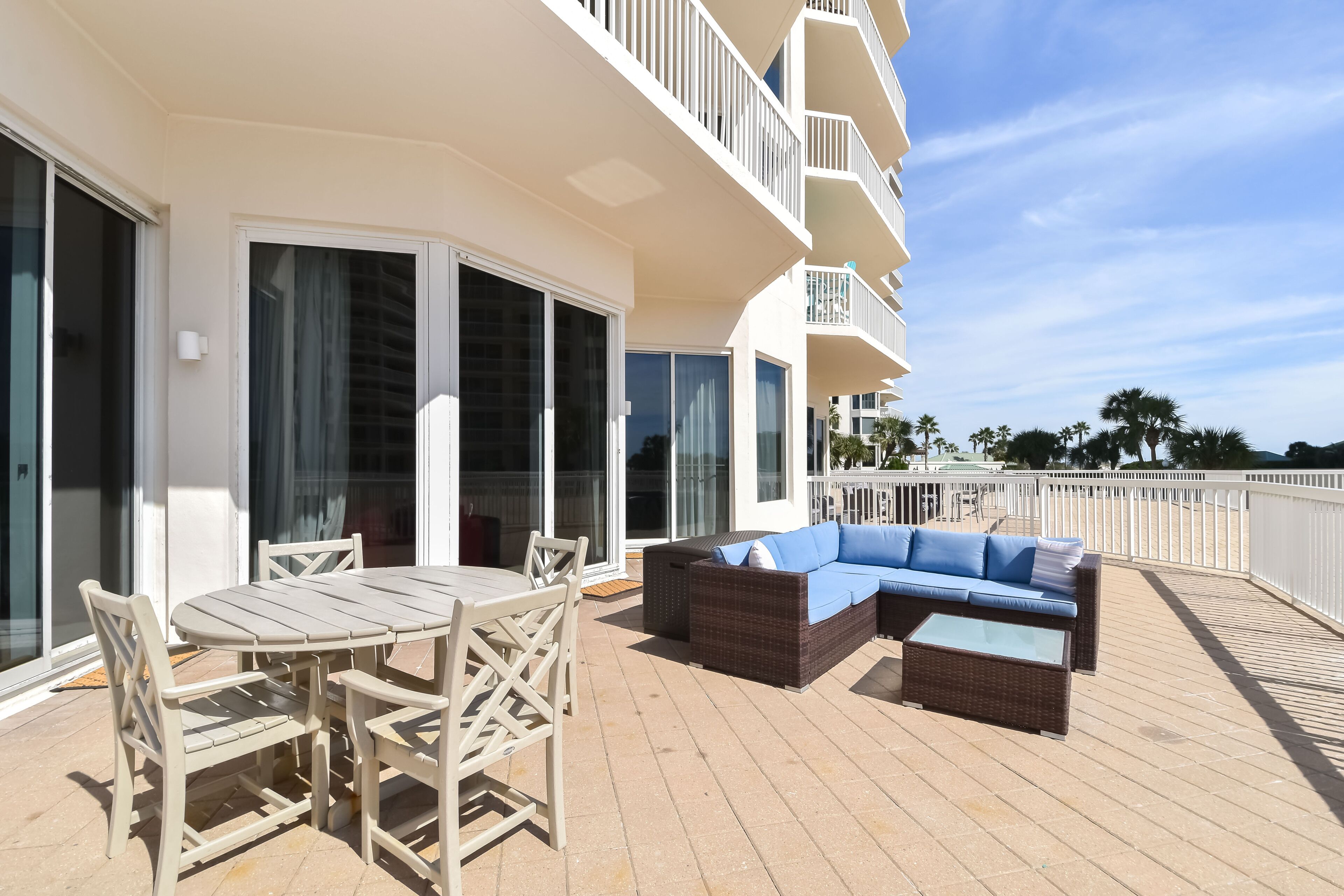 A balcony with a table and chairs, a sofa, and a railing.