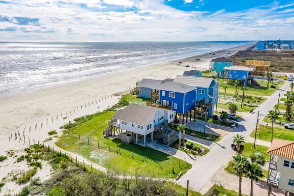 A coastal property with a large house, a beach view, and a road leading to the beach.