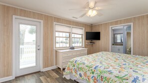 Une chambre à coucher avec un lit, une commode, un téléviseur et un ventilateur de plafond.