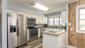 Una cocina moderna con electrodomésticos de acero inoxidable, encimera de granito y armarios blancos.