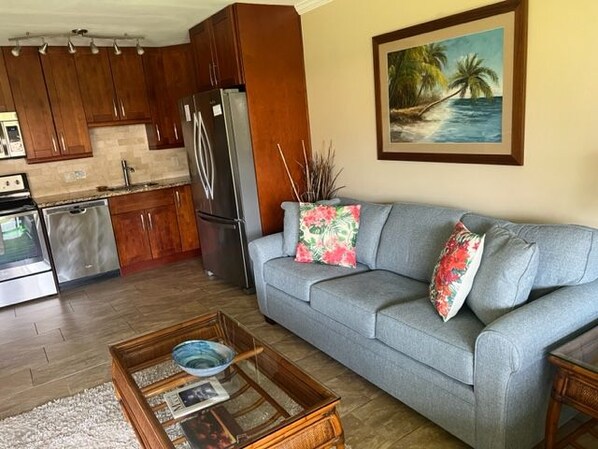 A living room with a grey sofa, wooden coffee table, and a painting of a beach scene.