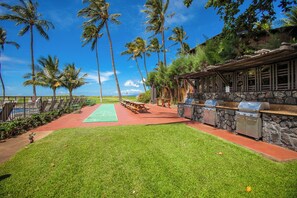 A well-maintained outdoor area with a green lawn, picnic tables, and barbecue grills.