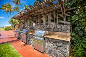 Uma área de churrasco ao ar livre, com paredes de pedra e uma pérgula de madeira.