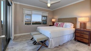 Un dormitorio con cama, banca, mesitas de noche y ventilador de techo.