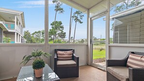 A covered patio area with wicker furniture, a glass table, and a potted plant. - Summer Lake Haven ~ Summer Specials! ~ 2Br/2.5Ba (Miramar Beach)