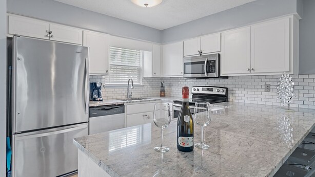 A modern kitchen with white cabinets, stainless steel appliances, and a marble countertop. - Summer Lake Haven ~ Summer Specials! ~ 2Br/2.5Ba (Miramar Beach)