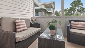 A balcony with wicker furniture, a potted plant, and a view of neighboring buildings. - Summer Lake Haven ~ Summer Specials! ~ 2Br/2.5Ba (Miramar Beach)