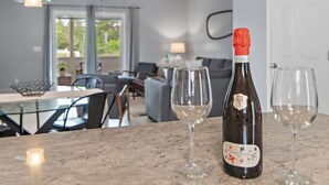 A bottle of Cuvée Clara wine on a marble countertop with two empty wine glasses beside it. - Summer Lake Haven ~ Summer Specials! ~ 2Br/2.5Ba (Miramar Beach)