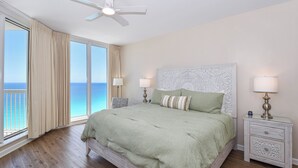 Ein Schlafzimmer mit einem Bett, Nachttischen, einem Deckenventilator und Blick aufs Meer.