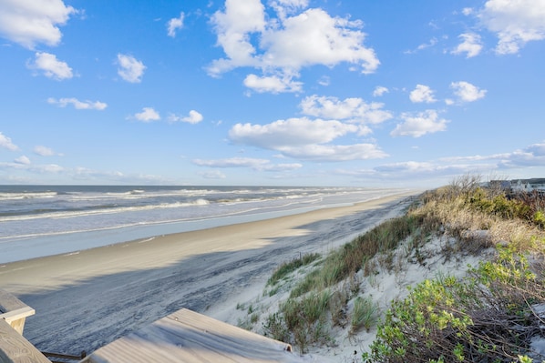 Une plage avec des dunes de sable et une promenade en bois.