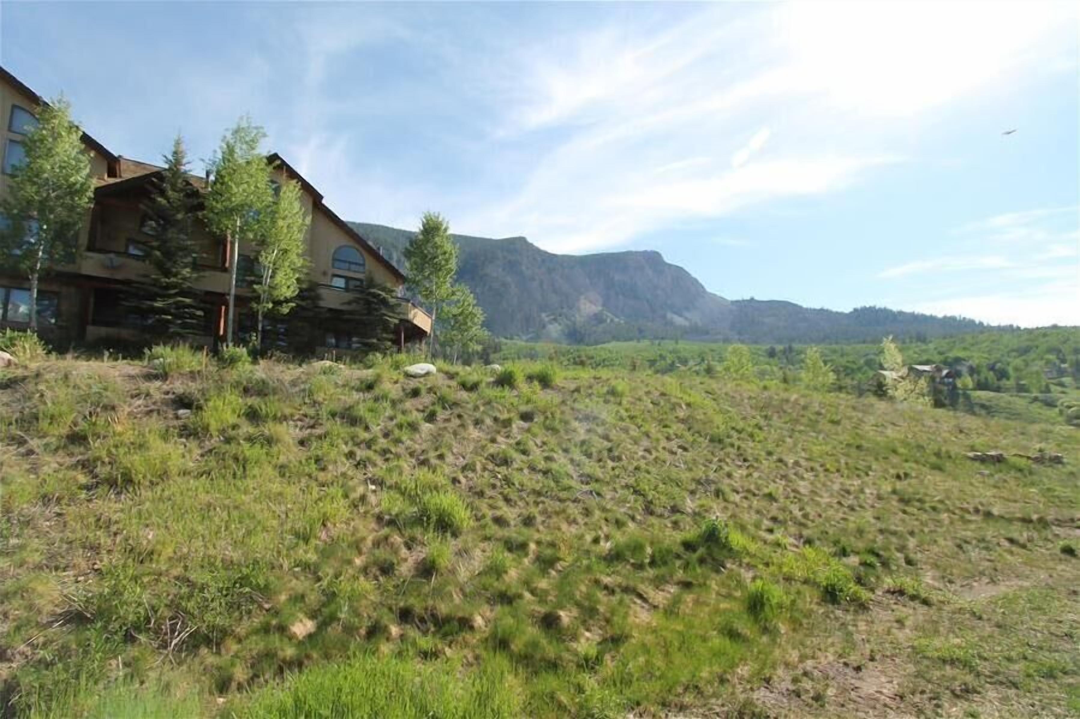 A rustic lodge with a large stone fireplace, a dining area, and a view of a mountain range.